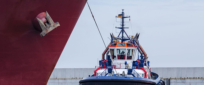 Schlepperschiff im Hamburger Hafen unterstützt ein Containerschiff als Symbol für strukturierte Investor Relations und Finanzkommunikation